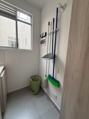 A small, clean bathroom with a window, a mop, a broom, and a trash bin. - Welcome to MA Cartagena • Playa • Piscina (Bolívar)