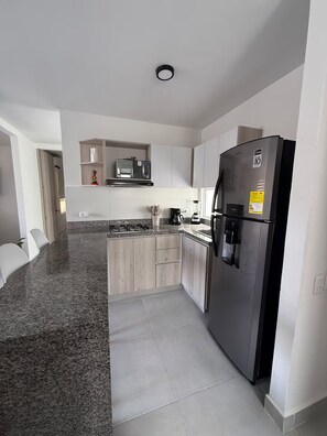 A modern kitchen with a stainless steel refrigerator, a microwave, and a gas stove. - Welcome to MA Cartagena • Playa • Piscina (Bolívar)