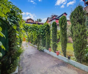 A pathway flanked by greenery and buildings. - Classic Valley Meadows (Srinagar)