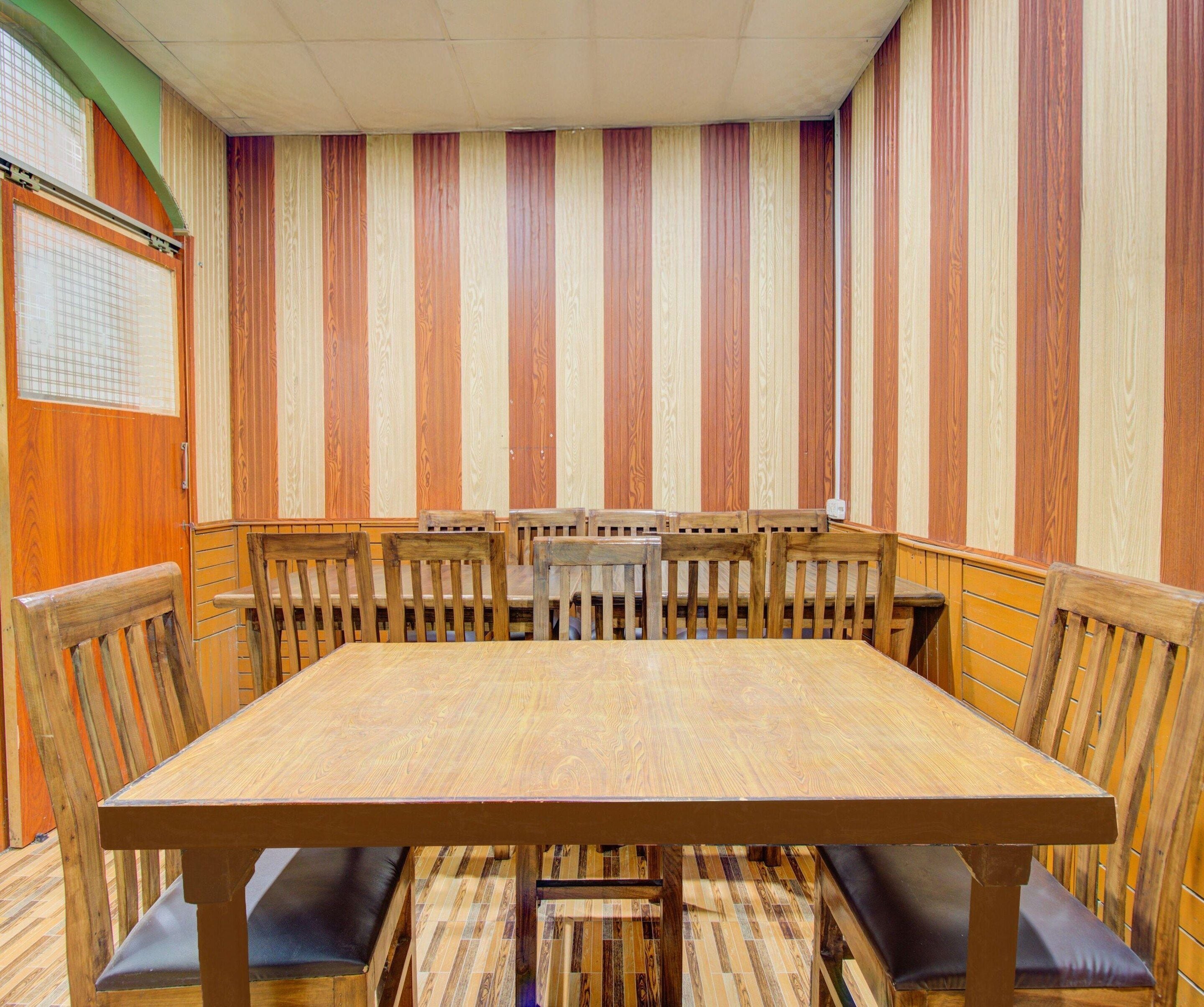 A conference room with a large wooden table, multiple chairs, and a striped wall.