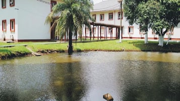 A building with a white facade and red trim, a covered outdoor area, and a pond with a bird.