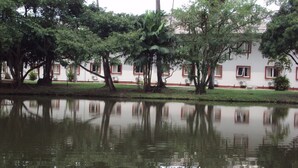 Un estanque tranquilo con reflejos de árboles y un edificio con ventanas de marco rojo.