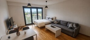Uma sala de estar moderna com uma cama, um sofá, uma mesa de centro e uma televisão.