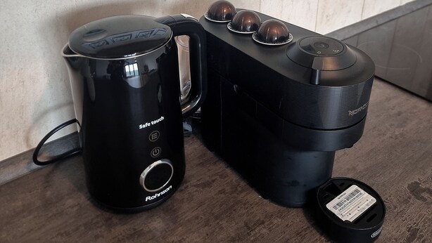 Una cafetera y una Keurig sobre una encimera de cocina con salpicadero de azulejos y un enchufe arriba.