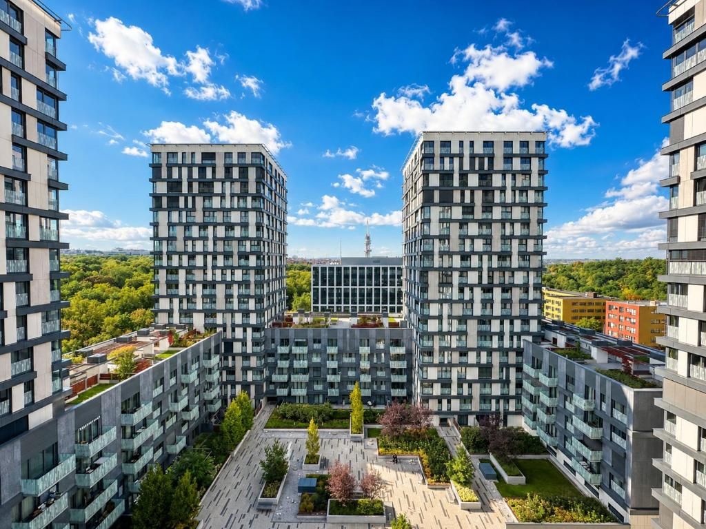 A modern apartment complex with a central courtyard, multiple balconies, and a clear view of the surrounding cityscape.