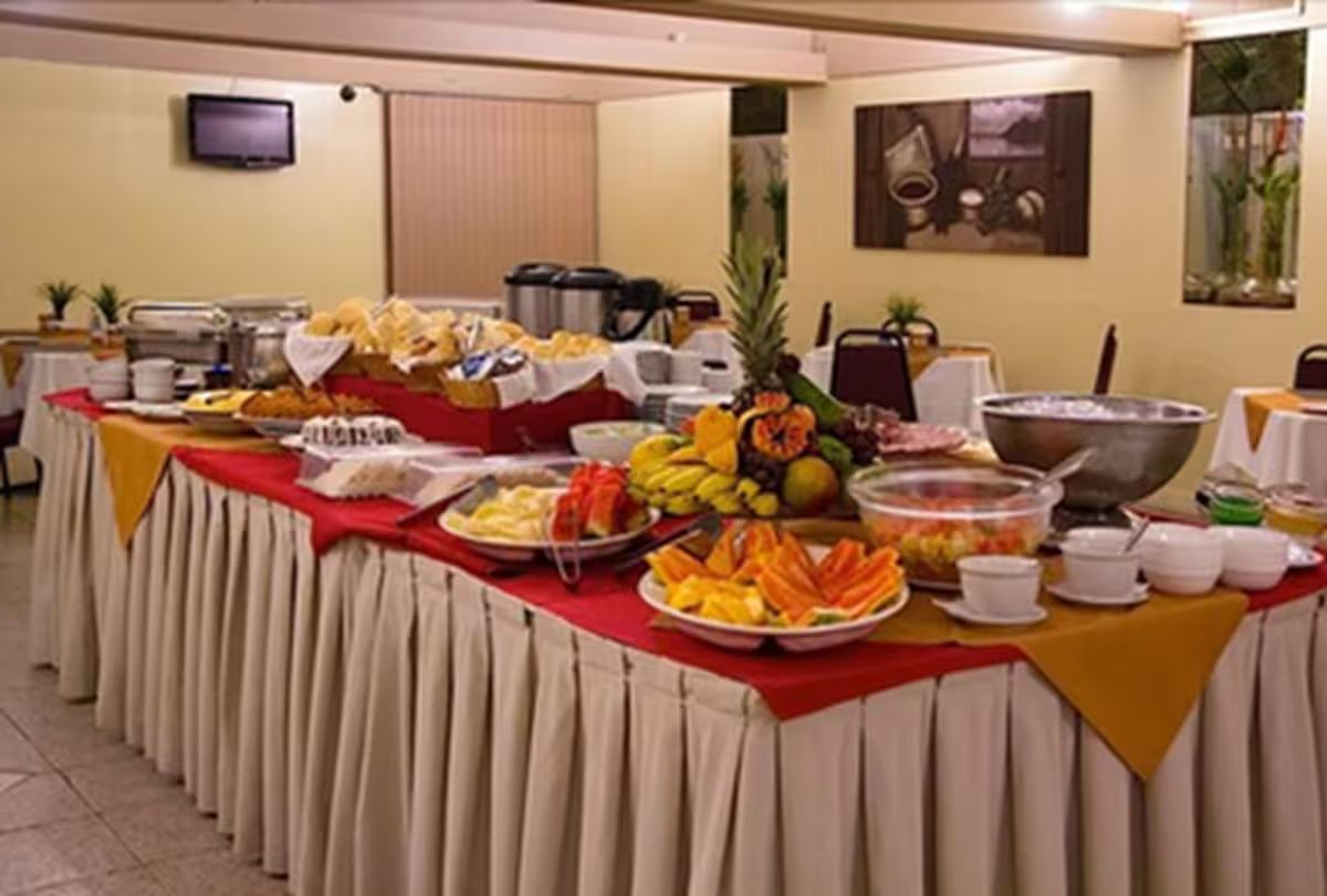 Disposição de buffet com diversos alimentos e uma panela grande, provavelmente para cozinhar ou aquecer comida.
