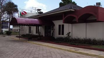 Um edifício com toldo vermelho, uma bandeira e uma área de entrada com azulejos.