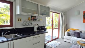 Une cuisine moderne avec un plan de travail noir, des meubles blancs et une porte-fenêtre coulissante donnant sur un balcon.