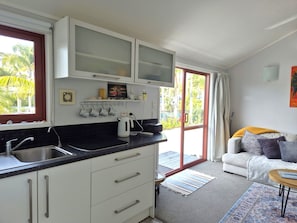 A modern kitchen with a black countertop, white cabinets, and a sliding glass door leading to a balcony.