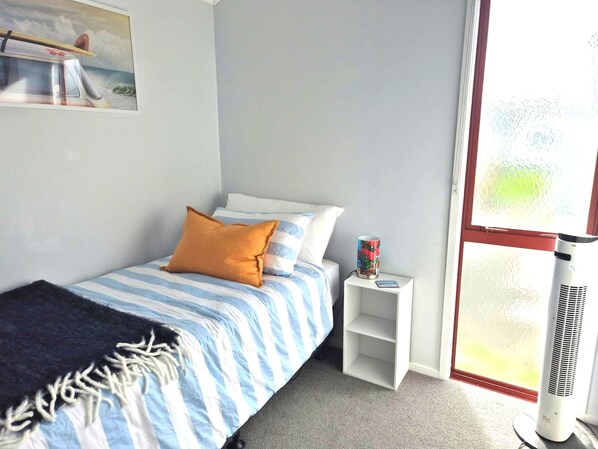Un dormitorio con cama, almohadas, una mesita de noche, un calefactor y una ventana con vistas.
