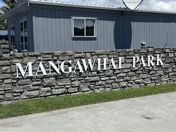 Un muro de piedra con el texto 'MANGAWHAI PARK', indicando un parque o zona recreativa.