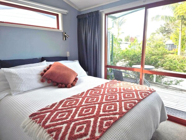 Un dormitorio con una cama grande, una ventana con cortinas y vistas a zonas verdes.