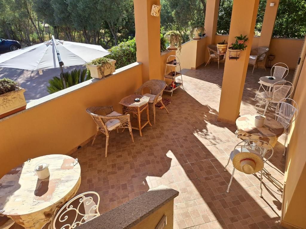 Una veranda esterna luminosa con mobili in vimini, un ombrello bianco e piante in vaso.