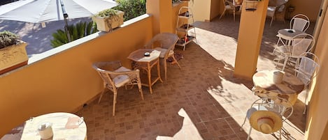 A balcony with wicker furniture, potted plants, and a white umbrella.
