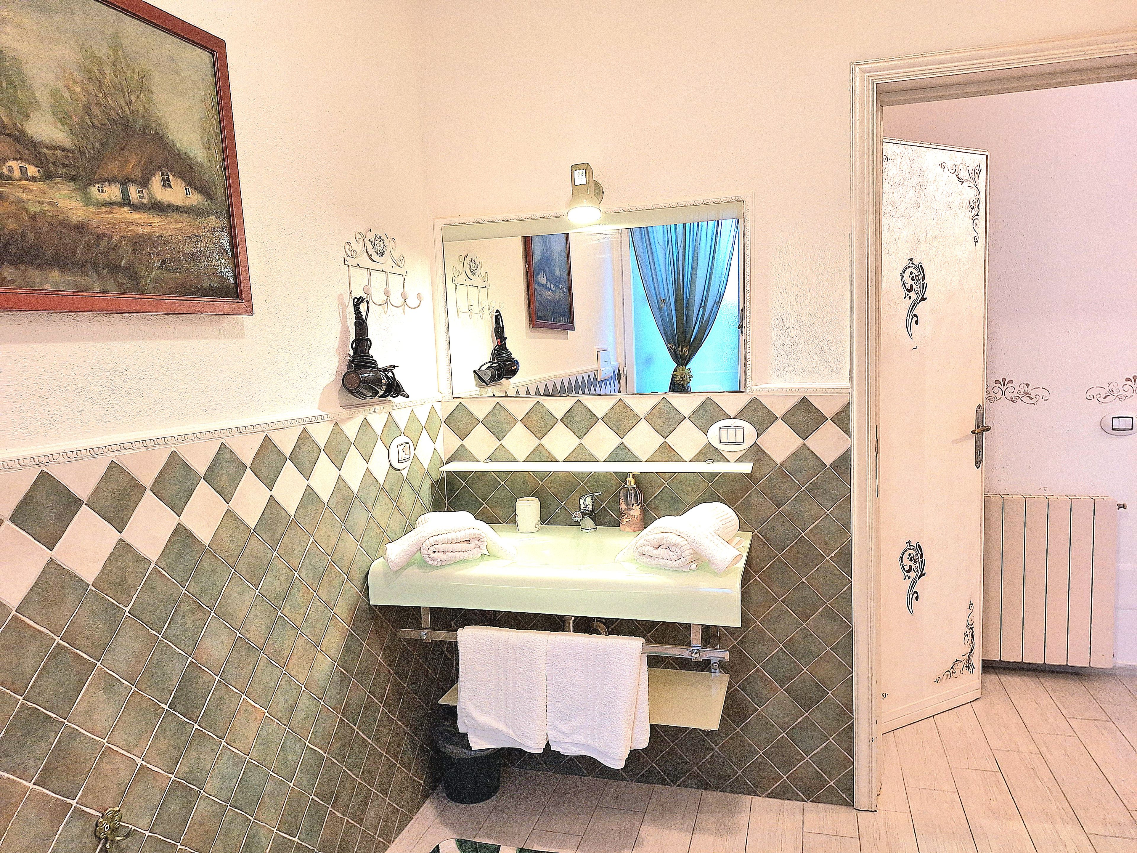 A bathroom with a sink, mirror, and tiled walls.
