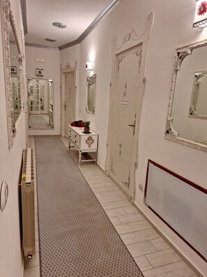 A hallway with ornate mirrors, a radiator, and a dresser with decorative items.
