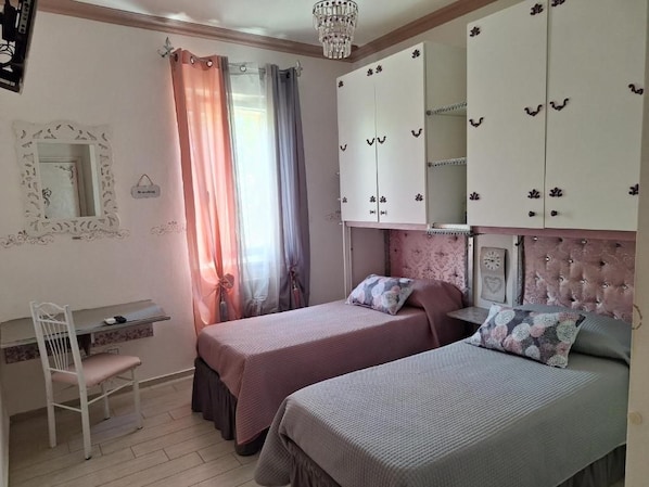 A bedroom with two beds, a desk, and a wardrobe.
