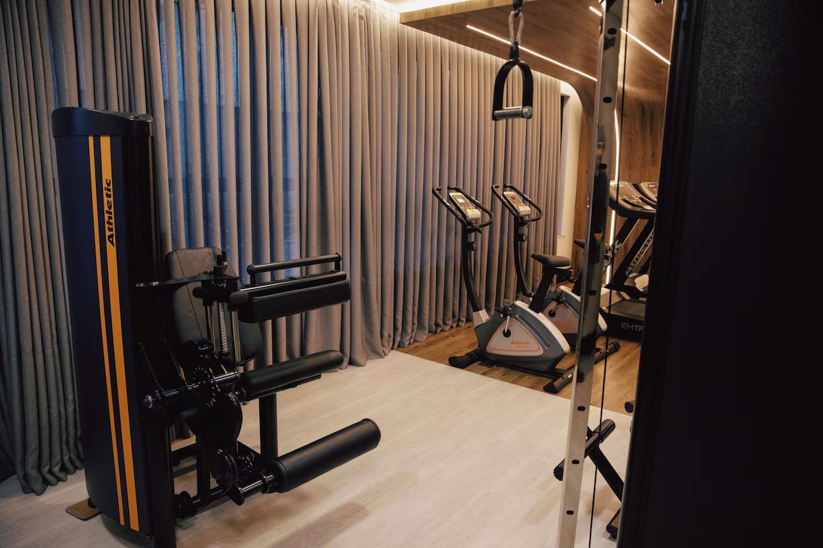 A gym with a squat rack, bench press, and elliptical machines.