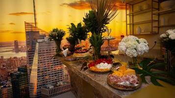 A buffet with various food items and a cityscape view in the background.