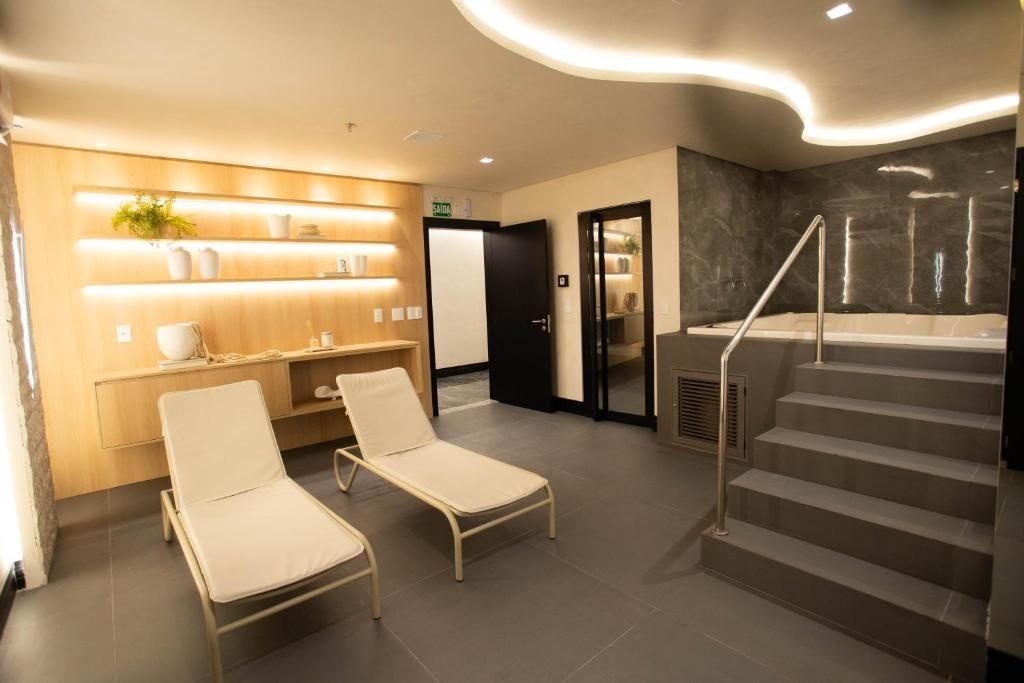Un hall d’hôtel moderne avec deux fauteuils, un comptoir d’accueil, un escalier et un espace dédié aux soins.