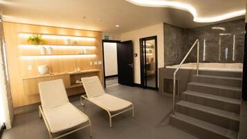 Un hall d’hôtel moderne avec deux fauteuils, un comptoir d’accueil, un escalier et un espace dédié aux soins.