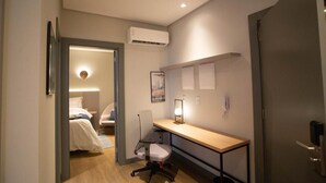 A compact hotel room with a bed, a desk, and a chair. There is a wall-mounted air conditioner and a framed picture on the wall. - Scenic Room Close to Perequê Beach – Walkable Stay with Free Breakfast Buffet! (Santa Catarina)