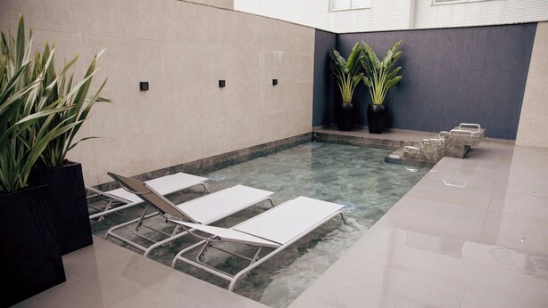 A spa area with a small pool, lounge chairs, and potted plants. - Ocean Room with Full Kitchen Perfect for Family Getaways Near Itapema Beach (Santa Catarina)