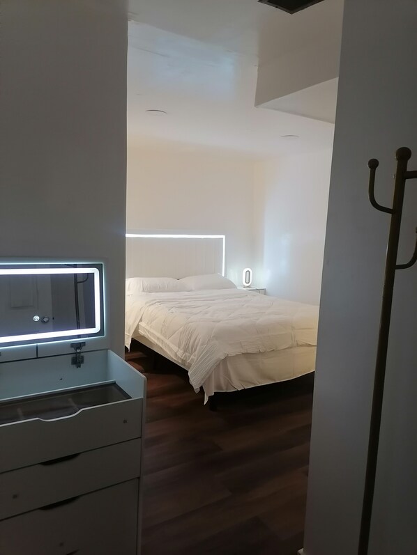 Un dormitorio con cama, mesita de noche, espejo y cómoda.