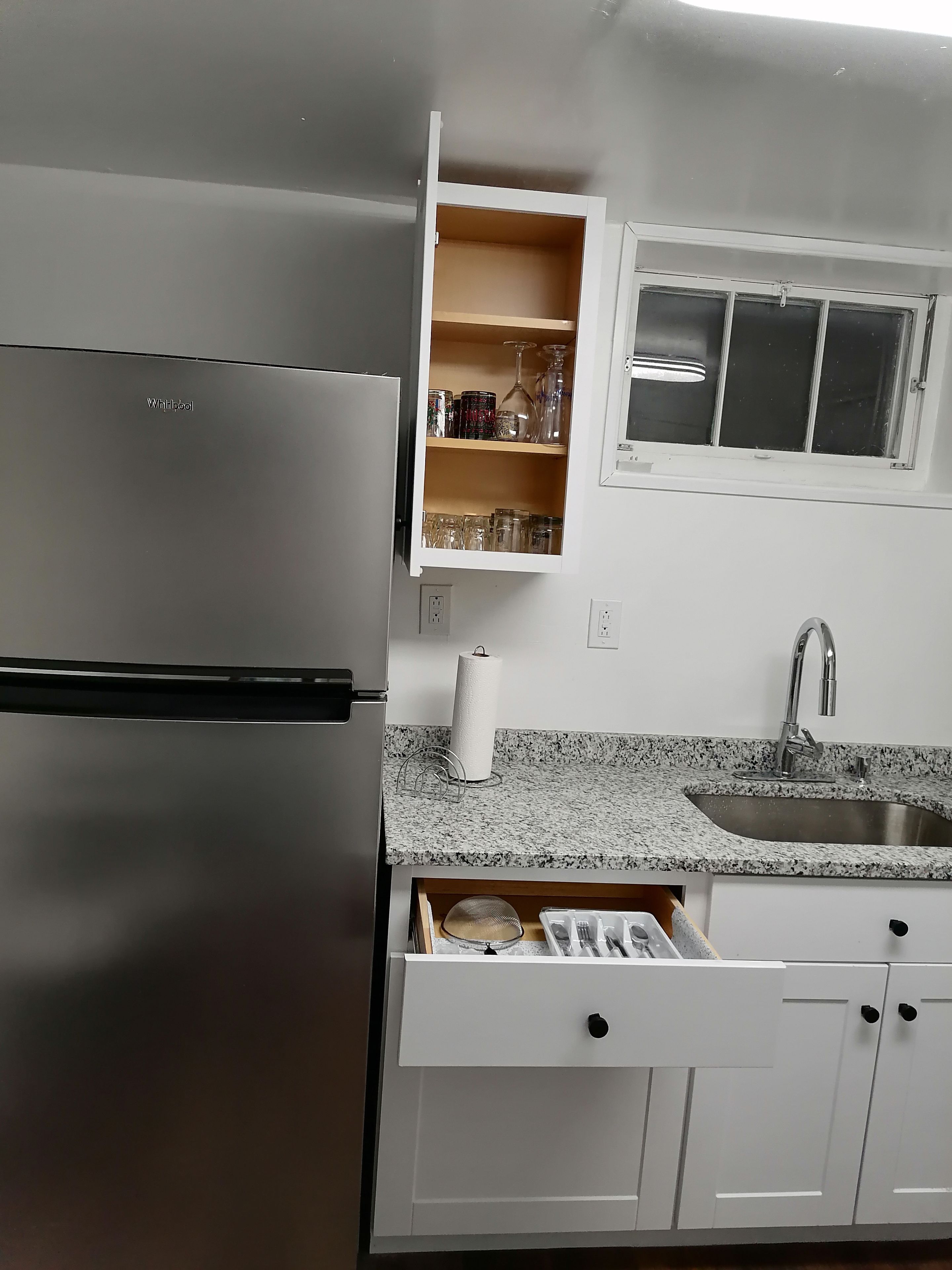 A kitchen with a built-in refrigerator, a granite countertop, a stainless steel sink, and a window above the sink.