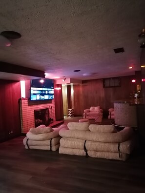 Ein Zimmer mit Kamin aus Backsteinen, einem an der Wand befestigten Flachbildfernseher und einem Stapel weißer Kissen.