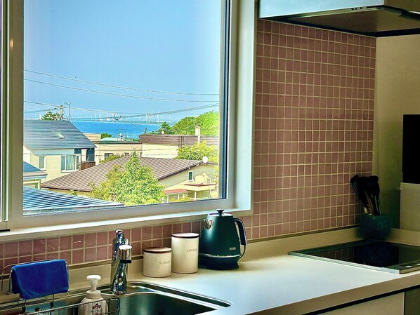 A kitchen with a window view of a residential area and a bridge.