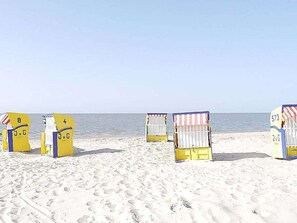 Beach chairs with numbers and letters, arranged on a sandy beach with the ocean in the background. - Holiday Apartment With 1 Bedroom (Cuxhaven)