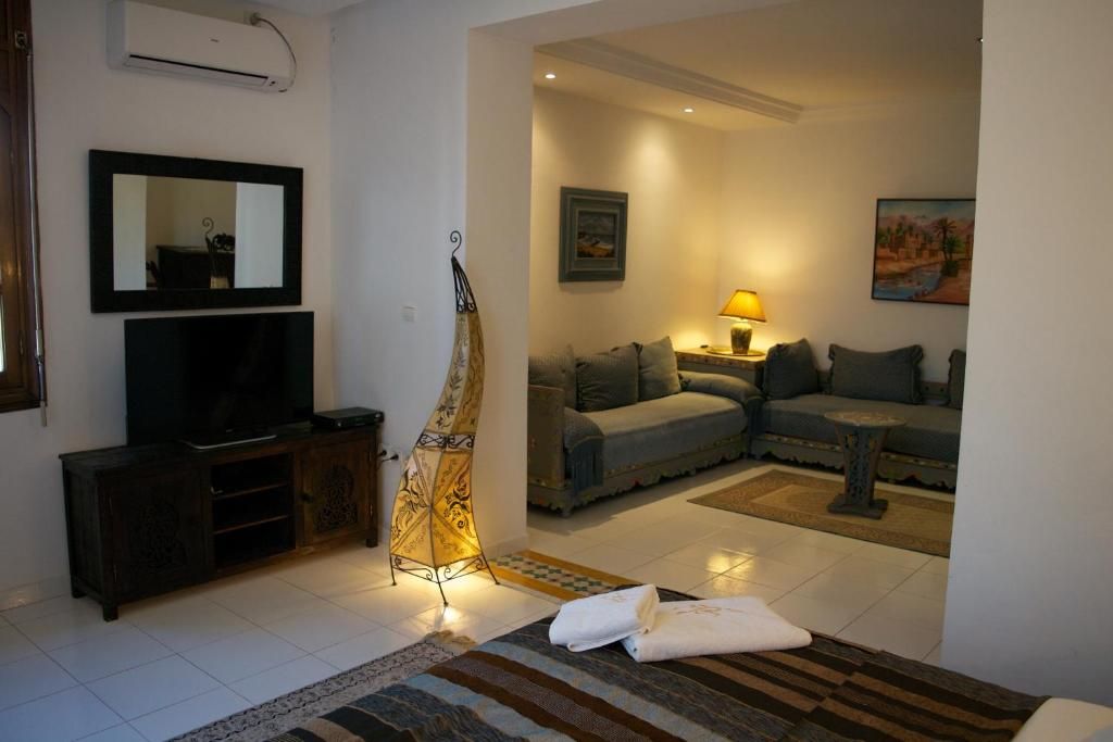 Een woonkamer met een bank, een televisie, een lamp en een sierlamp.