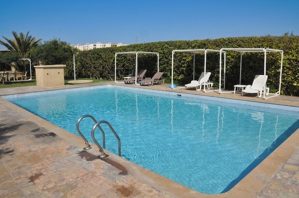 A swimming pool with lounge chairs and a pergola structure. - Gite Nadia (Oulad Azzouz)