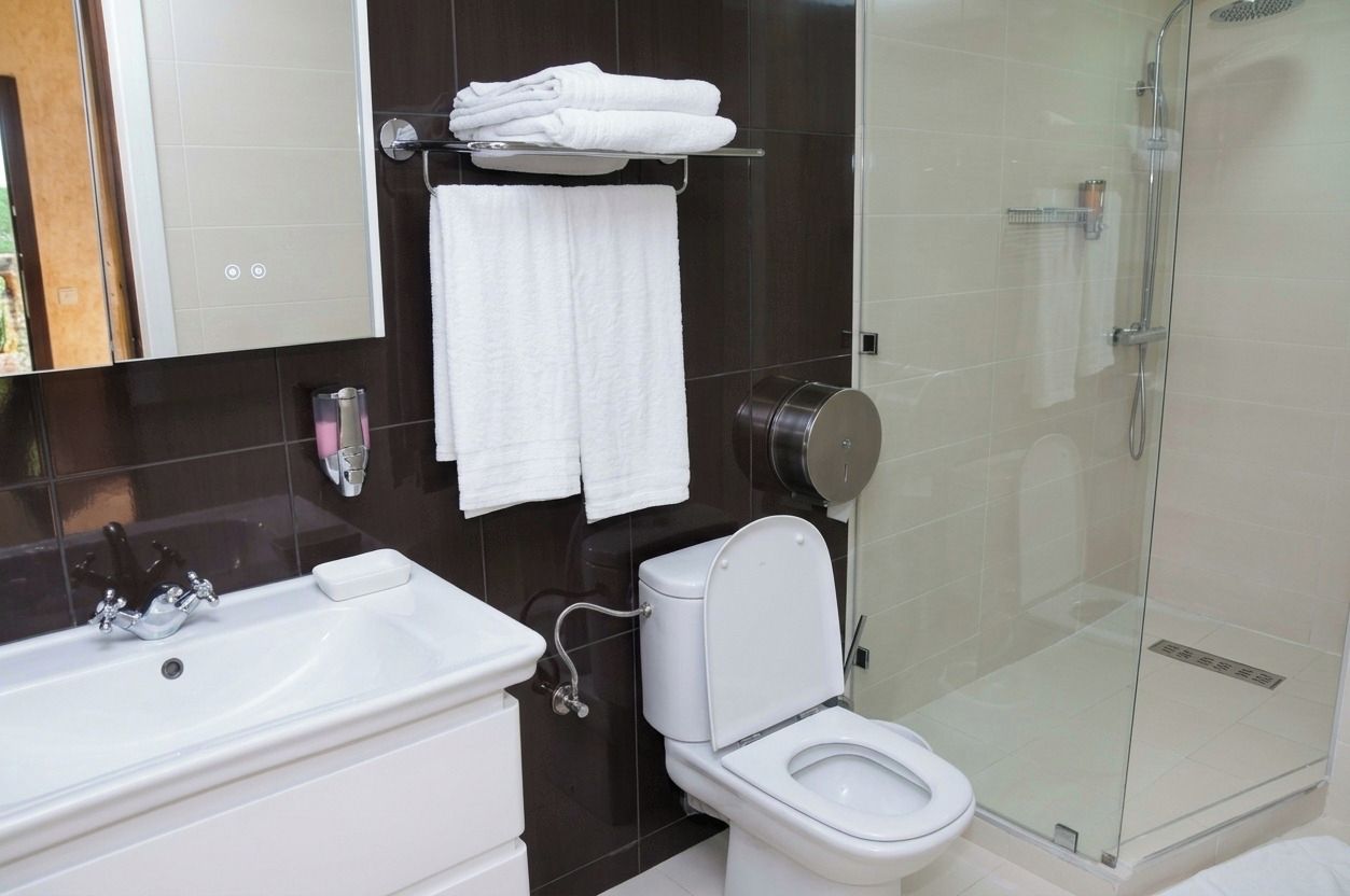 A modern bathroom with a glass-enclosed shower, a white toilet, and a sink with a soap dish.