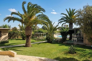 A courtyard with palm trees, a pool, and outdoor seating. - Gite Nadia (Oulad Azzouz)