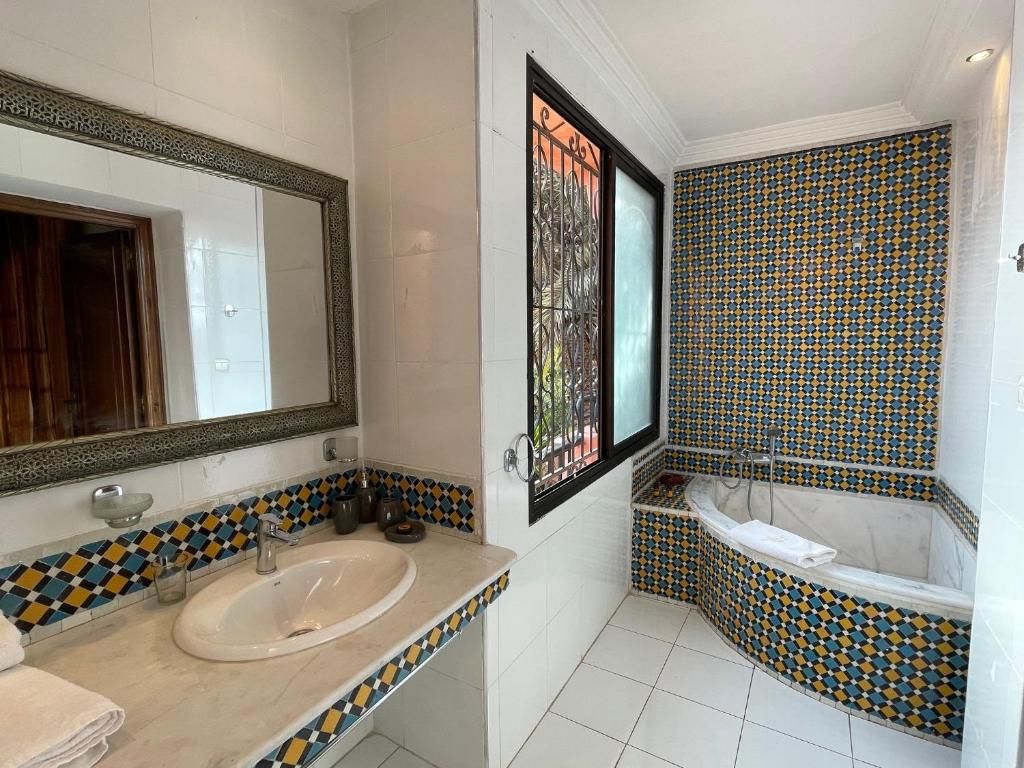 A bathroom with a sink, mirror, and bathtub.
