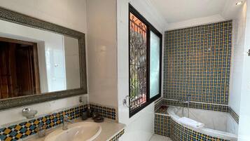 A bathroom with a sink, mirror, and bathtub.