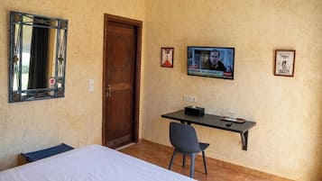 Una habitación de hotel con una cama, un escritorio, una silla, un televisor y una puerta.