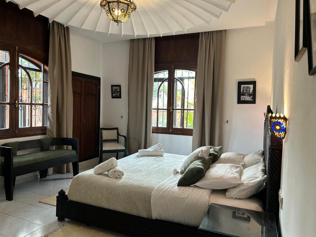 A bedroom with a bed, a bench, and a window with curtains.