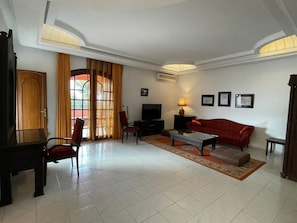 A living room with a sofa, television, and a piano. - Gite Nadia (Oulad Azzouz)