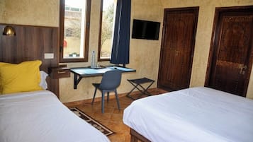 A hotel room with two beds, a desk, a chair, a TV, and a window with curtains.