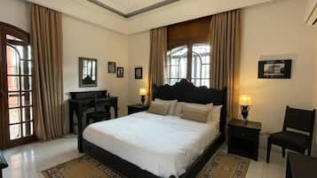 Een slaapkamer met een groot bed, twee nachtkastjes, een bureau en een stoel.