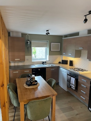 A compact kitchen with a dining table, chairs, and a window. - Luxury River Tyne | Newcastle Contractor Stay | Monday to Friday (Gateshead)