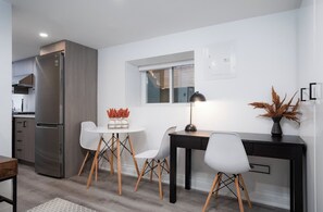 A modern kitchen with a built-in refrigerator, a dining area with a round table and chairs, and a small window. - Sun-Drenched West End Retreat | Walk to High Park (Toronto)