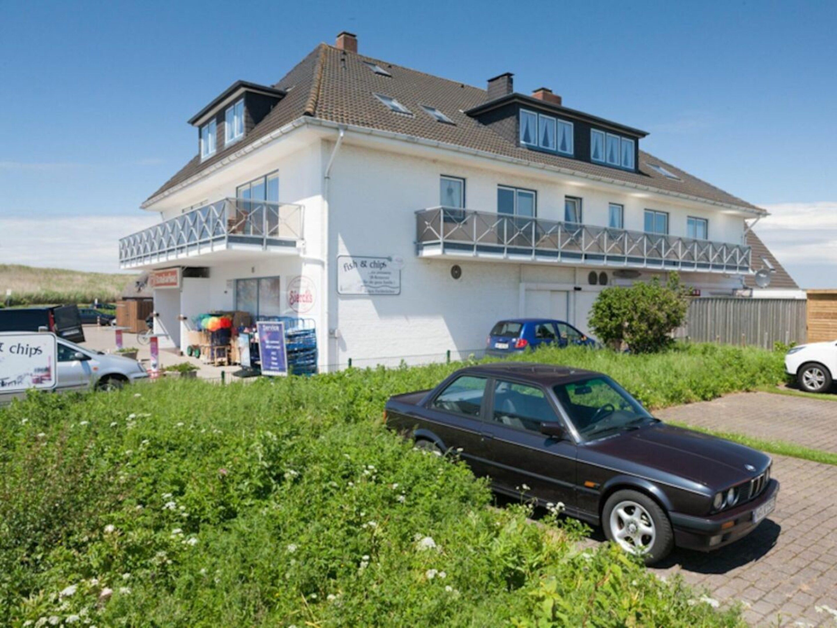 Ein zweistöckiges Gebäude mit einem Schild für 'fish & chips' und einem parkenden Auto davor.