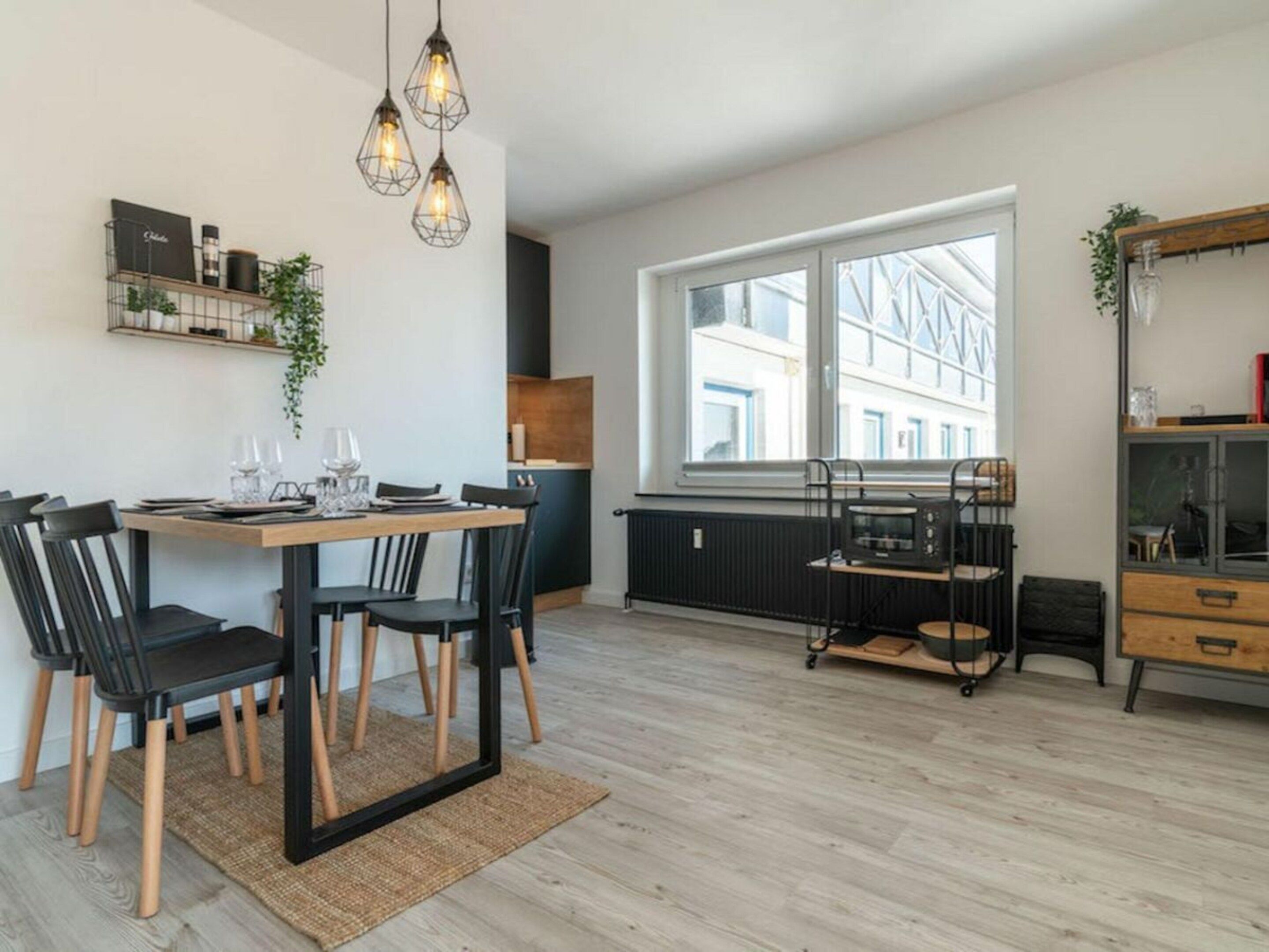 Een moderne keuken met een eethoek, grote ramen en een inbouwmagnetron.