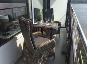 Ein Balkon mit Korbmöbeln, einem Tisch und einem Blumentopf.