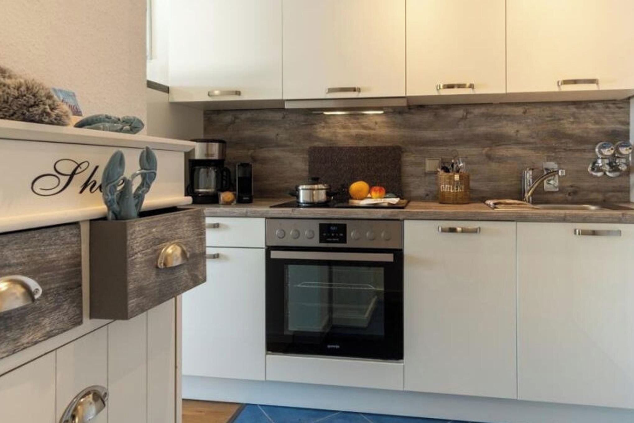 A modern kitchen with white cabinets, a built-in oven, and a coffee maker.