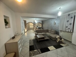 Una sala de estar moderna con un sofá modular, una mesa de centro y un comedor al fondo.